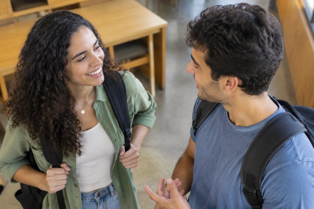 Dois estudantes de mochila continuam a discussão no corredor depois da sessão